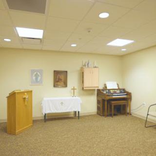 A quiet chapel space featuring a small altar and an organ.