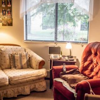 A cozy living room with a sofa, armchair, and a small lamp by the window.