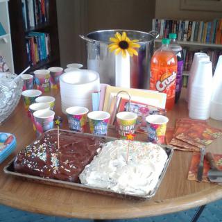 A table set up for a celebration with cakes, snacks, and drinks.
