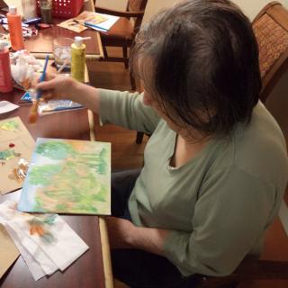 A woman painting at a table, engaging in a creative hobby indoors.