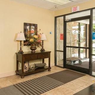 A welcoming lobby entrance with a decorative table, lamps, and a glass door.