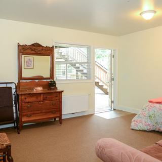A bedroom interior with a vintage dresser, open door, and a bed.
