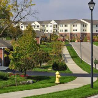A peaceful suburban neighborhood with apartment buildings and landscaped lawns.