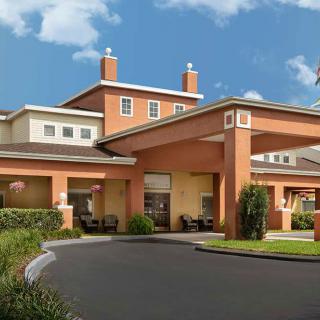A welcoming hotel entrance with a covered driveway and landscaped surroundings.