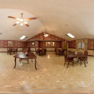 A spacious, empty dining room with wooden tables and chairs, featuring ceiling fans and decorative wall accents.