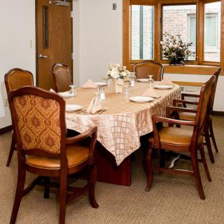 A neatly arranged dining room with a table set for dinner, featuring elegant chairs and a floral centerpiece.