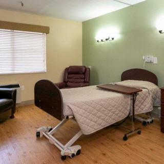 A hospital room with a bed, chair, and medical equipment.