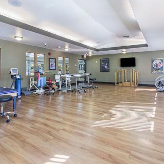 A modern and spacious gym with fitness equipment and a wooden floor.