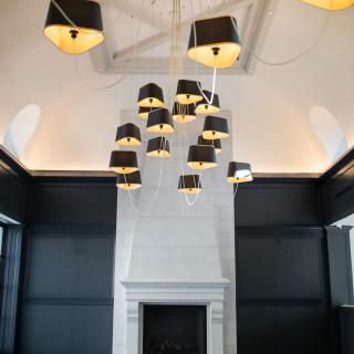 A luxurious interior featuring a modern chandelier and a tall white fireplace.