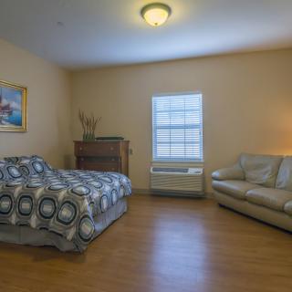 A cozy bedroom with a bed, sofa, and wooden flooring.