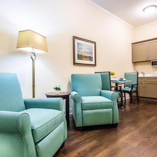 A cozy living room with teal armchairs, a table, and a standing lamp.