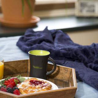 A cozy breakfast tray with a croissant, berries, a mug of coffee, and a glass of juice.
