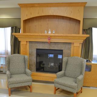 A cozy living room setting with two comfortable chairs facing a wooden fireplace.