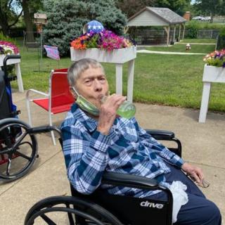 A senior enjoying a snack in a wheelchair surrounded by blooming flowers.