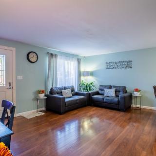 A cozy living room with a sectional sofa, hardwood flooring, and natural light from the window.