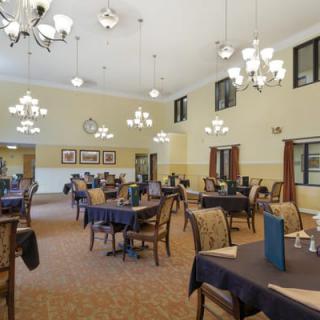 A spacious dining room with elegant chandeliers and neatly arranged tables and chairs.