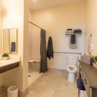 A modern bathroom with a shower, toilet, and sink in neutral tones.