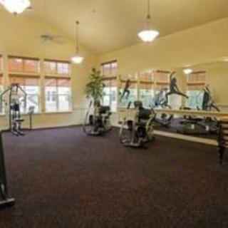 A well-lit gym with various exercise equipment and large mirrors.