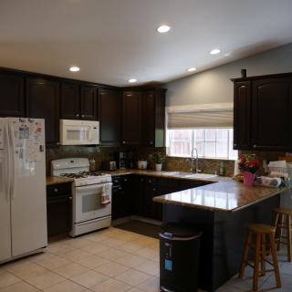 A modern kitchen with dark cabinets and various appliances.
