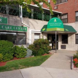 Entrance to a care center with green awning and landscaped surroundings.