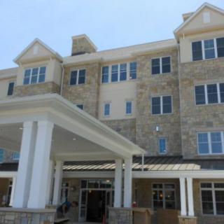 A modern stone facade building with a prominent entrance and multiple windows.