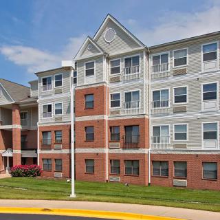 A modern residential apartment building with red brick and gray siding.