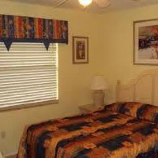A cozy bedroom with colorful bedding, artwork on the walls, and natural light pouring in through the window.
