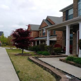 A suburban residential street lined with brick houses and well-maintained front yards.