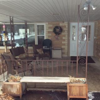 A cozy covered patio with seating and decorative plants.