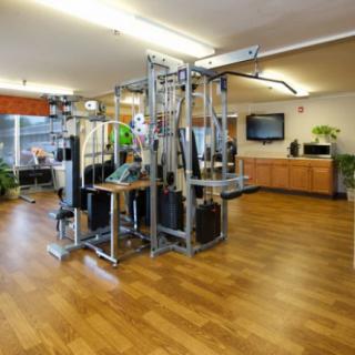 A well-equipped gym interior featuring a multigym machine and wooden flooring.