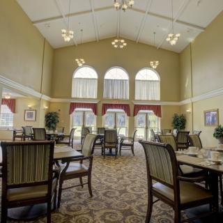 A spacious dining room with elegant furnishings and large windows allowing natural light to fill the space.