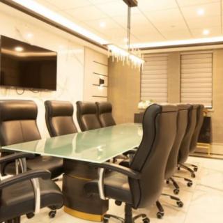 A modern conference room with a sleek glass meeting table and comfortable chairs.