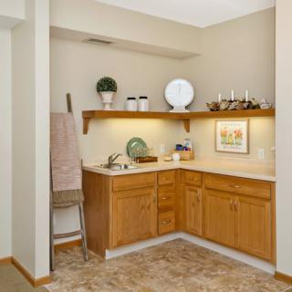 A small kitchen area with wooden cabinets, decorated shelves, and a countertop.