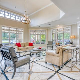 A modern and luxurious living room with large windows, elegant furniture, and a chandelier.