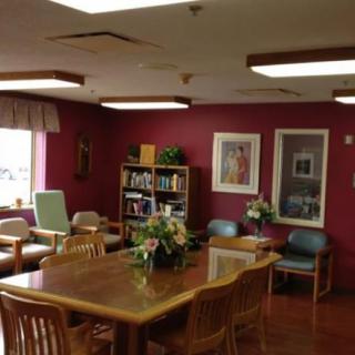A cozy room with a wooden table and chairs, adorned with floral arrangements and books on the shelf.