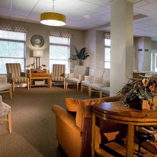A cozy waiting room with comfortable seating, a round table, and soft lighting.