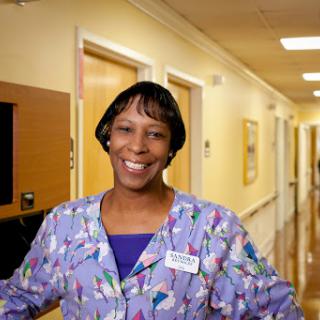 A cheerful nurse welcomes you in a hospital corridor.