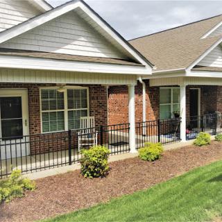 A view of a well-maintained residential building featuring porches and landscaped gardens.