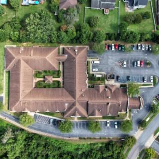 An aerial view of a large building with a surrounding parking lot and nearby roads.