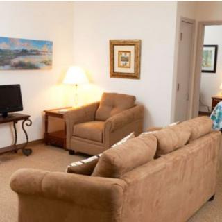 A cozy living room with a sofa, armchair, lamp, and television.