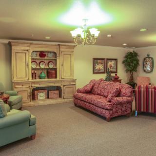A cozy living room with comfortable seating, decorative items, and a traditional bookshelf.