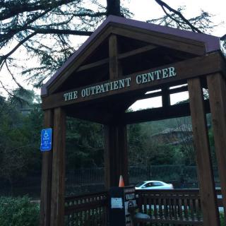 Entrance to The Outpatient Center with wooden signage and surrounding nature.