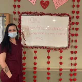 A healthcare professional stands beside a festive Valentine's Day decoration, emphasizing love and care in the workplace.