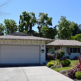 A charming residential house with a garage, surrounded by lush greenery.