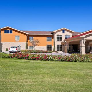 A modern residential building surrounded by a well-maintained lawn under a clear blue sky.