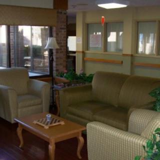 A cozy living room area with sofas, chairs, a coffee table, and large windows.