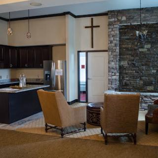 A cozy lounge area featuring modern armchairs and a sleek kitchen with a stone wall accent.
