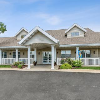 A large house with a front porch and neatly landscaped surroundings under a clear blue sky.