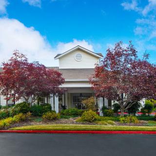 A well-landscaped building with colorful trees and a clear blue sky.