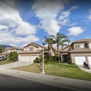 A suburban neighborhood with two-story houses and palm trees lining the street.